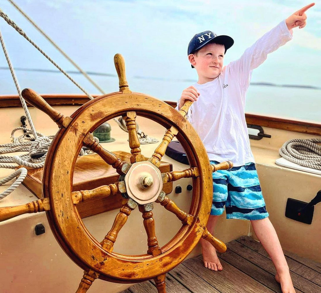 Young boy at the wheel of Lazy Jack.